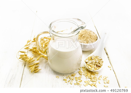 Milk oatmeal in jug on light wooden board Milk oatmeal in jug on light wooden board 49120769