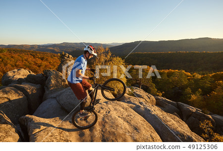 Sportsman cyclist balancing on back wheel on trial bicycle 49125306