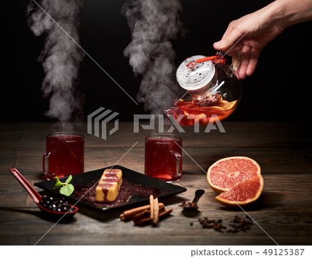 Hand pouring hot tea from glass kettle. Steaming tea in glasses. Delicious Japanese sweet dessert on 49125387