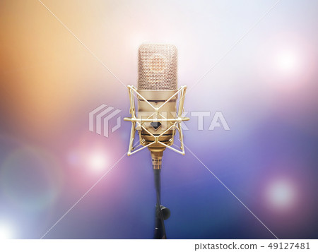 microphone on a stand, a blurry colored background microphone on a stand, a blurry colored background 49127481