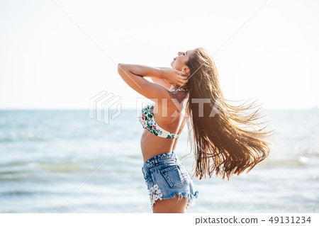 Model posing with long shiny hairs at seashore Model posing with long shiny hairs at seashore 49131234