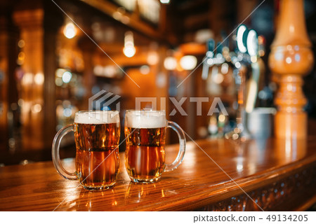 Two beer mugs on wooden bar counter, nobody 49134205