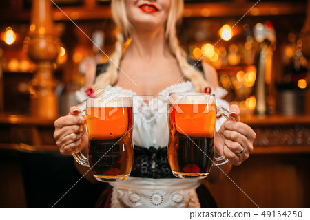 Sexy waitress holds two mugs of fresh beer in pub Sexy waitress holds two mugs of fresh beer in pub 49134250