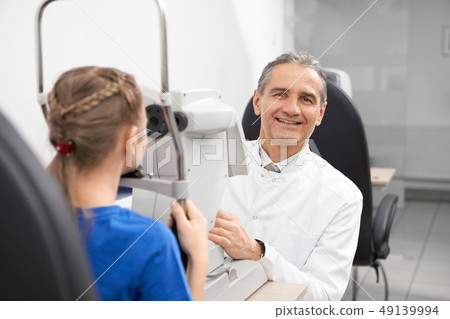 Experienced ophthalmologist doing checkup on slit lamp. 49139994