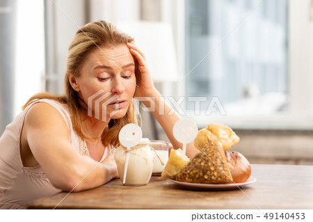 Housewife sitting at the table and looking at foods evoking allergies 49140453