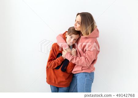 Mothers day, children and family concept - teen boy hugging his mom on white background Mothers day, children and family concept - teen boy hugging his mom on white background 49142768