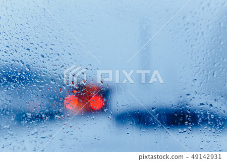 Traffic abstract in rain. Traffic seen from inside a car. Rain drops on windshield and car tail Traffic abstract in rain. Traffic seen from inside a car. Rain drops on windshield and car tail 49142931