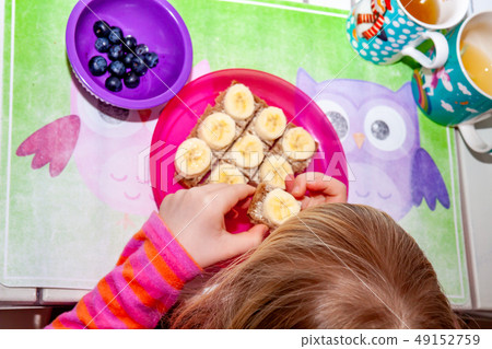 Little girl eating banana bread for breakfast Little girl eating banana bread for breakfast 49152759
