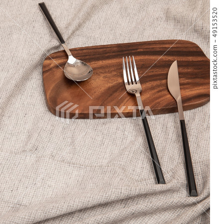A knife, spoon, and fork on a cutting board 49153520