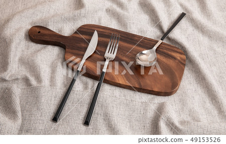 A knife, spoon, and fork on a cutting board A knife, spoon, and fork on a cutting board 49153526
