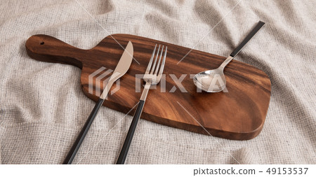 A knife, spoon, and fork on a cutting board 49153537