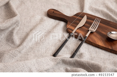 A knife, spoon, and fork on a cutting board 49153547