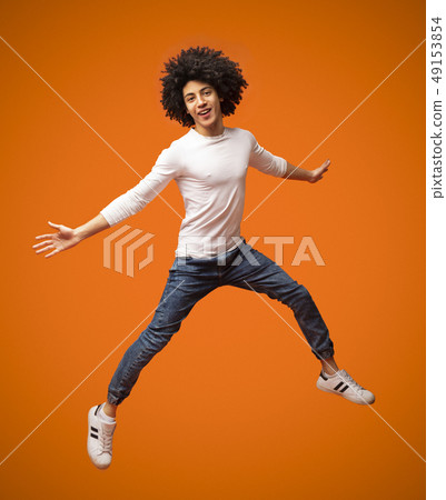 Cheerful african-american curly guy jumping in air 49153854
