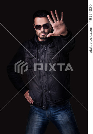 Handsome young man in sunglasses shows stop gesture. 49154820