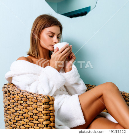 Woman in bathrobe drinking tea in spa salon. Woman in bathrobe drinking tea in spa salon. 49155222