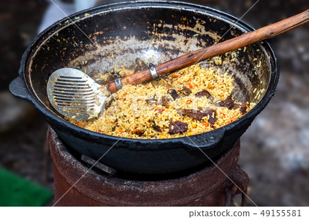 Cooking traditional Uzbek pilaf in a large 49155581