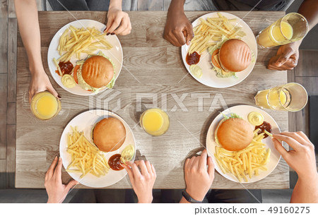 Plates of hamburgers, french fries, juice glasses on table. 49160275