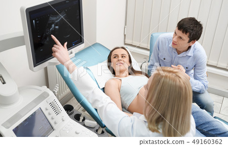 Doctor on consultation with pregnant woman and her husband. Doctor on consultation with pregnant woman and her husband. 49160362