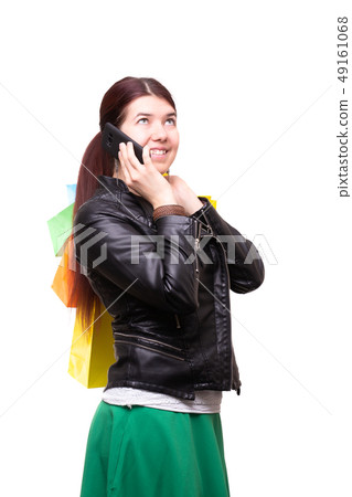 Photo of brunette talking on phone while standing with multi-colored shopping Photo of brunette talking on phone while standing with multi-colored shopping 49161068