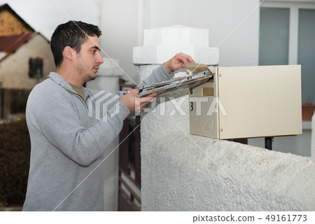 Man putting newspaper from the mailbox Man putting newspaper from the mailbox 49161773