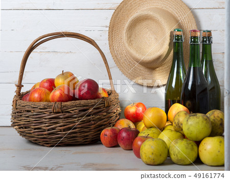 three bottles of cider and basket of apples three bottles of cider and basket of apples 49161774