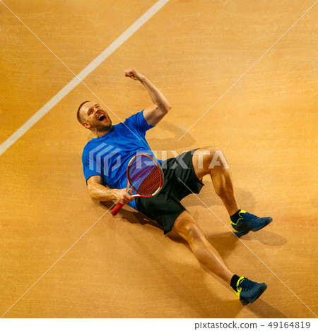 Portrait of a handsome male tennis player celebrating his success at court Portrait of a handsome male tennis player celebrating his success at court 49164819