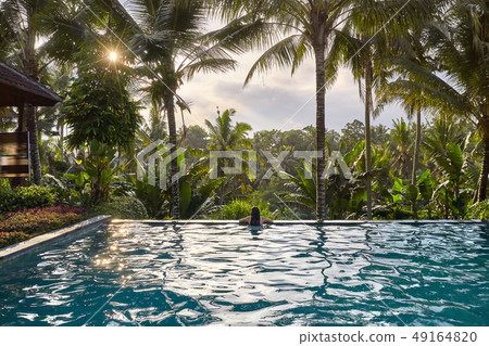 Woman in white swimsuit in outdoor pool on green jungle background Woman in white swimsuit in outdoor pool on green jungle background 49164820