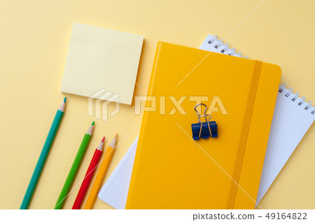 Bright notebook and pencils on yellow background. Bright notebook and pencils on yellow background. 49164822