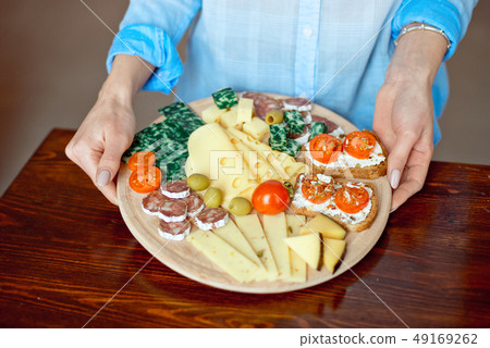 Close-up woman holds a cheese plate in her hands Close-up woman holds a cheese plate in her hands 49169262