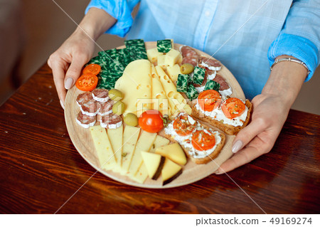 Close-up woman holds a cheese plate in her hands Close-up woman holds a cheese plate in her hands 49169274