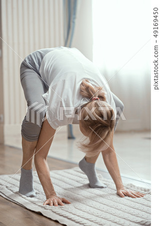 European Looking Woman Over 50 Years Old Doing Yoga at Home in the Living Room. European Looking Woman Over 50 Years Old Doing Yoga at Home in the Living Room. 49169450