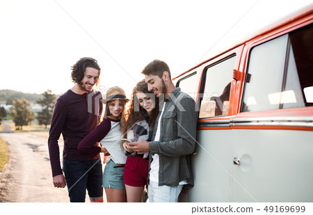 A group of young friends on a roadtrip through countryside, using smartphone. 49169699