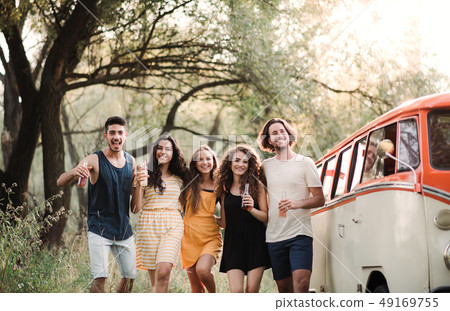 A group of friends standing outdoors on a roadtrip through countryside, holding bottles. A group of friends standing outdoors on a roadtrip through countryside, holding bottles. 49169755