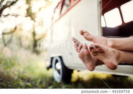 A group of young friends on a roadtrip through countryside, feet sticking out. 49169758