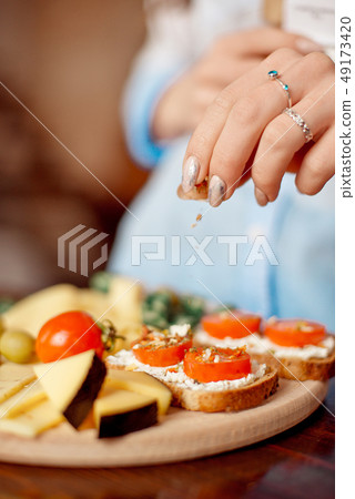 Close-up female hands hold cutting board with prosciutto, salami, cheese, bread sticks, cherry Close-up female hands hold cutting board with prosciutto, salami, cheese, bread sticks, cherry 49173420
