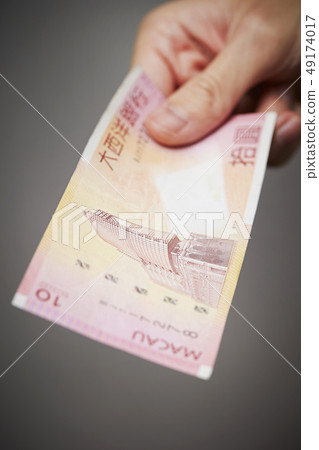 Macao currency Male hand with Pataca banknote 49174017