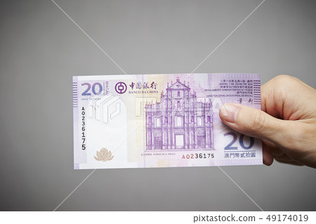 Macao currency Male hand with Pataca banknote 49174019