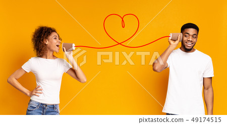 Young black couple with can phone on orange background Young black couple with can phone on orange background 49174515