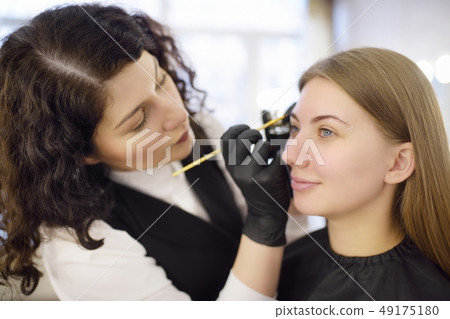 Cosmetologist painting eyebrows by brush. 49175180