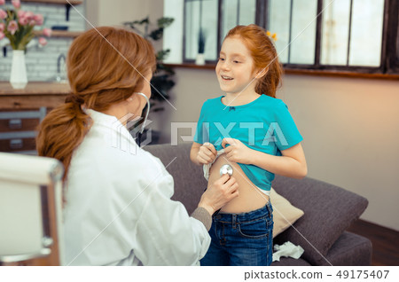 Positive cute girl showing her belly to the doctor Positive cute girl showing her belly to the doctor 49175407