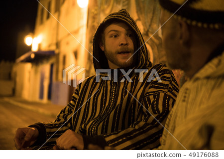 Two Man in Traditional moroccan djellaba walking on the street of Asilah Medina, on Atlantic Coast 49176088
