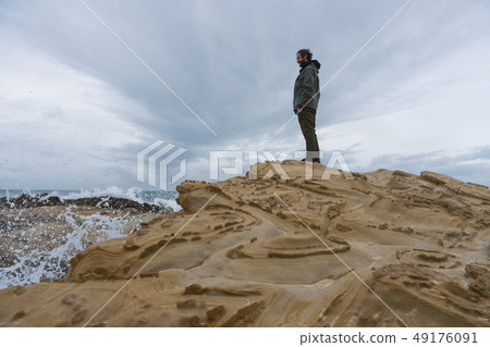 Traveler on the rocks near the sea looking far away at horizon. Rocky Atlantic Ocean Coastline and 49176091