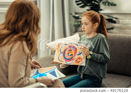 Cute pleasant girl holding a colorful painting Cute pleasant girl holding a colorful painting 49176129
