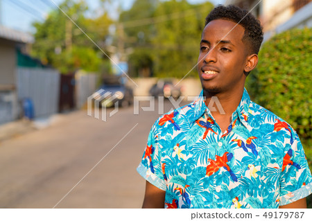 Face of happy young African tourist man with Afro hair thinking outdoors Face of happy young African tourist man with Afro hair thinking outdoors 49179787