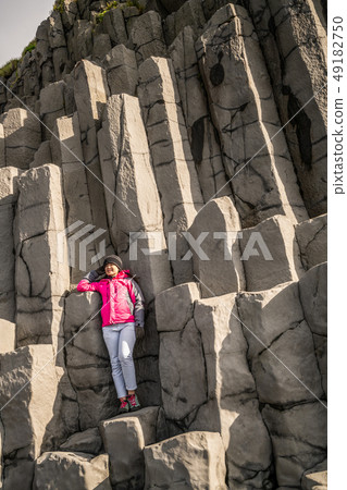 Traveler on hexagonal rocks in Vik, Iceland. 49182750