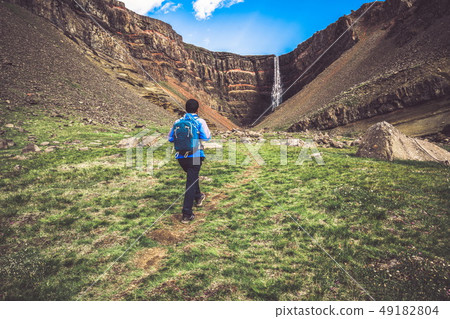 Traveler hiking at Hengifoss Waterfall, Iceland. 49182804