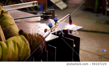 A worker start heating up the detail with a machine for the bending 49187229