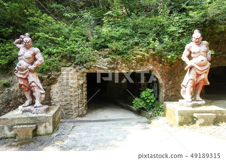 一個金黃明亮的人的雕像在一個洞前面的在Hanibe洞 49189315