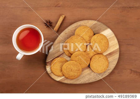 Gingersnaps, shot from the top with a cinnamon stick, an anise star, a cup of tea, and a place for 49189369