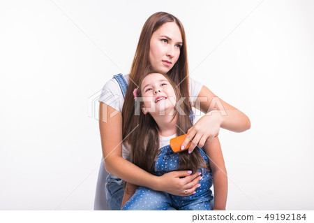 Family, motherhood and parent concept - mother combing her little daughter's hair isolated on white Family, motherhood and parent concept - mother combing her little daughter's hair isolated on white 49192184
